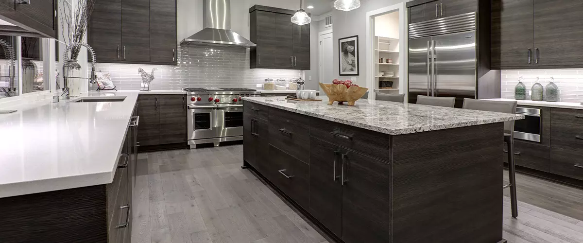 Modern gray kitchen features dark gray flat front cabinets paired with white quartz countertops and a glossy gray linear tile backsplash