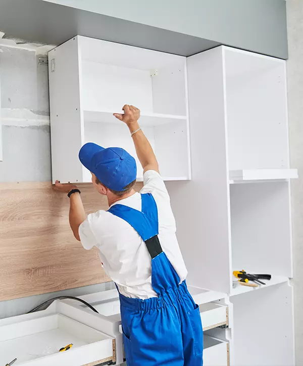 cabinet installer in the kitchen. worker assembling white kitchen cabinets