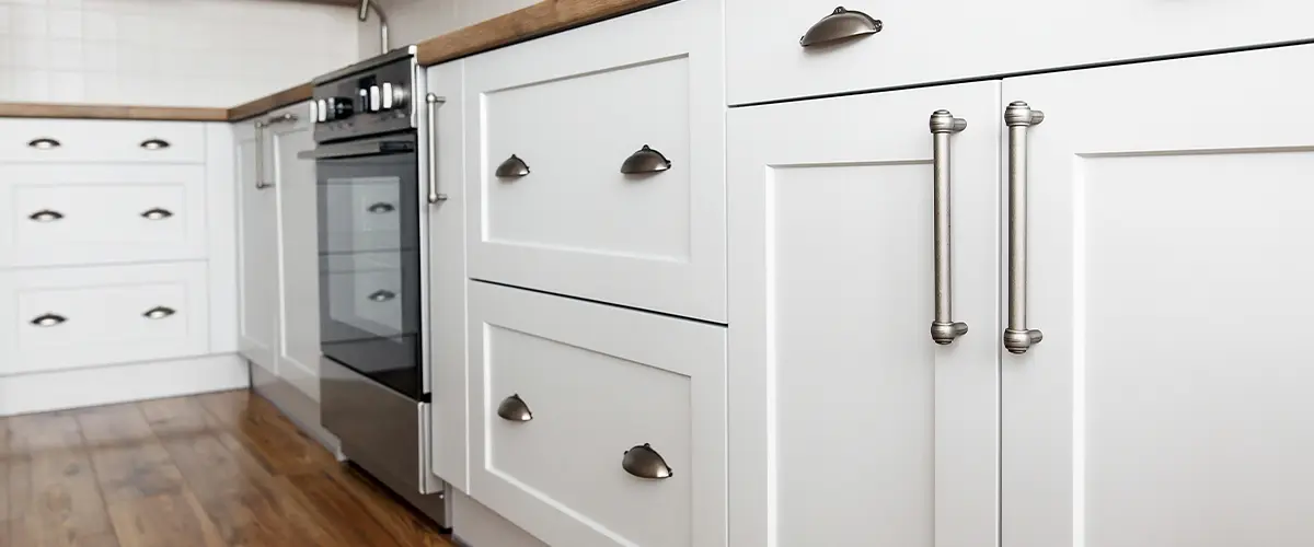 Close-up of modern white kitchen cabinet design in Montreux, with stainless steel handles and wood countertops, showcasing a stylish and functional design.