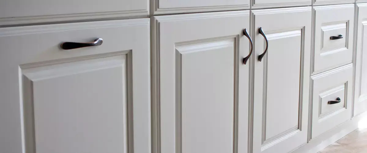 Close-up of white kitchen cabinets with elegant handles, showcasing classic cabinetry design and high-quality finishes.