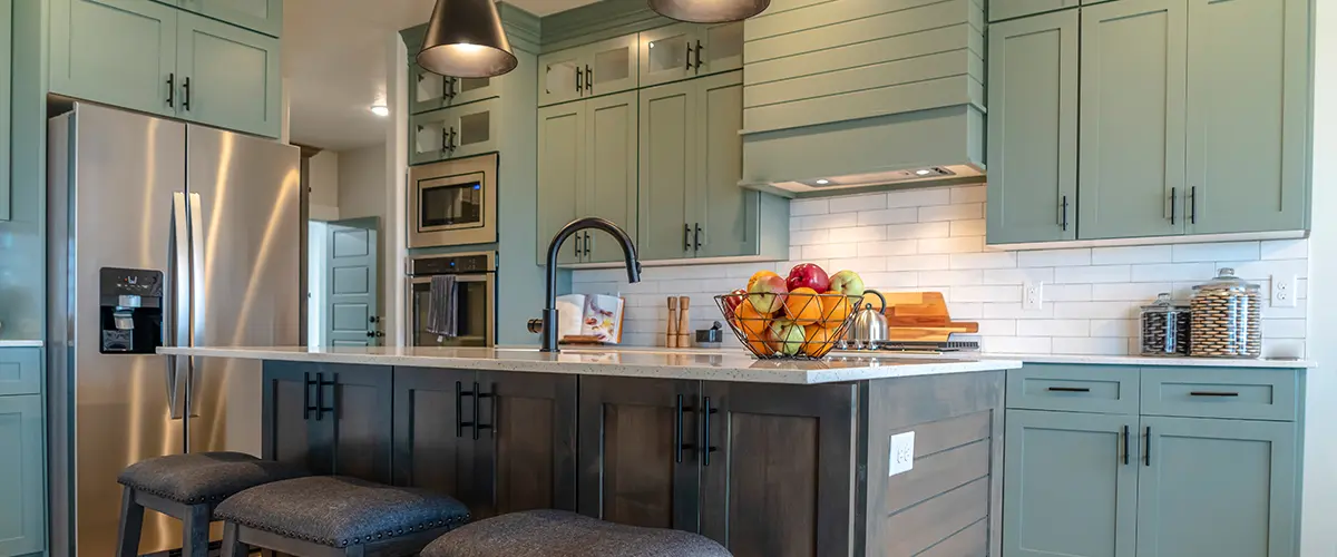 Modern kitchen in Cold Springs, with teal cabinetry, stainless steel appliances, large island with seating, and stylish pendant lighting.