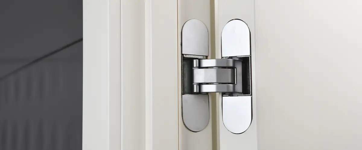 Close-up of a concealed hinge on a white cabinet door, designed for seamless and sleek cabinet installation.