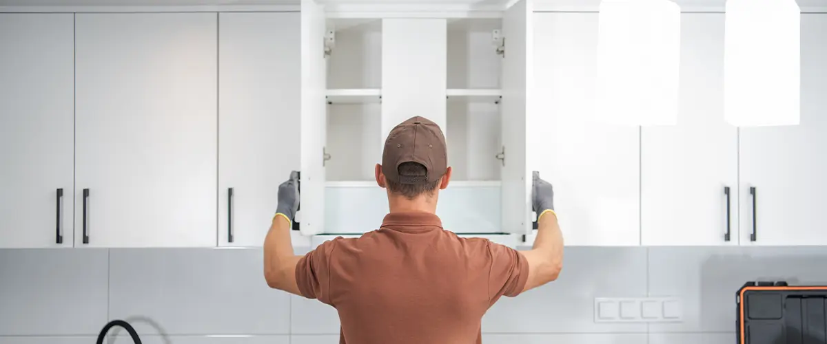 Contractor installing kitchen cabinets in a modern white kitchen, tools and equipment on the countertop, focusing on home renovation.