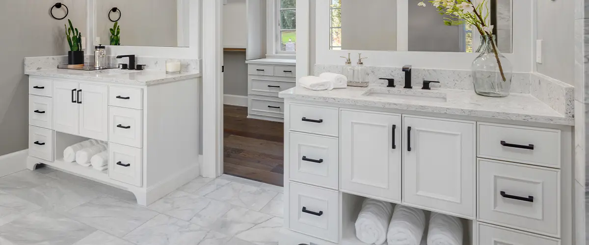 Luxurious white bathroom with double sinks, marble countertops, and elegant lighting fixtures and bathroom cabinets.