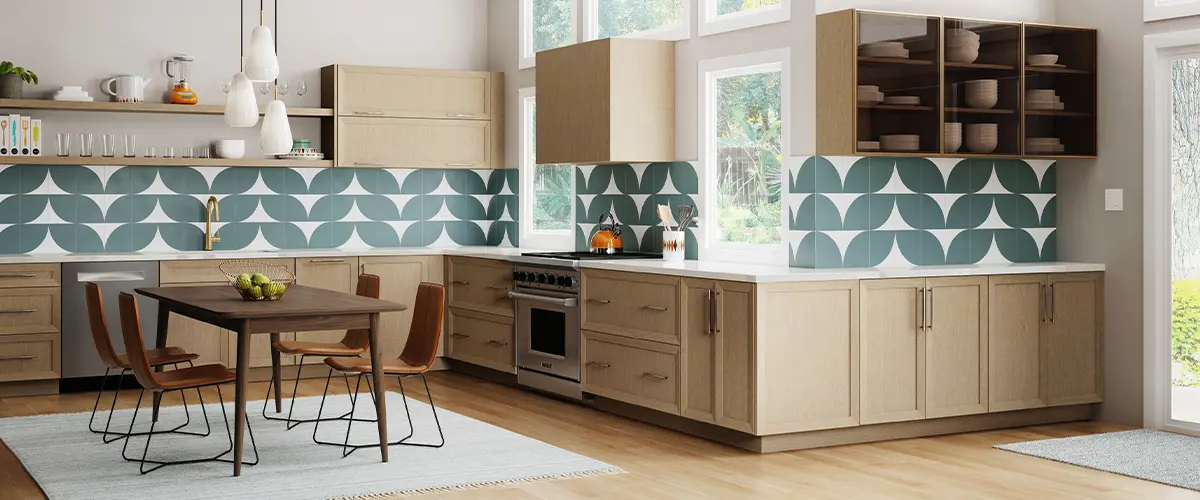 Modern kitchen with light wood cabinets, green geometric backsplash, and ample natural lighting.