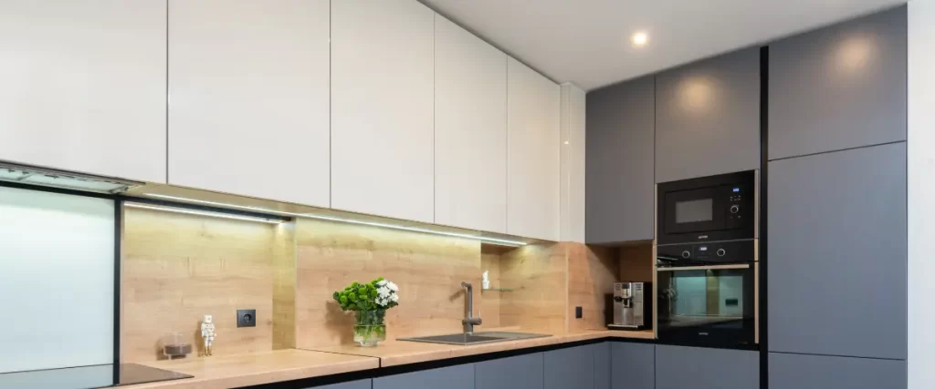 A sleek contemporary kitchen with a mix of wood and dark cabinets, under-cabinet lighting, and built-in appliances