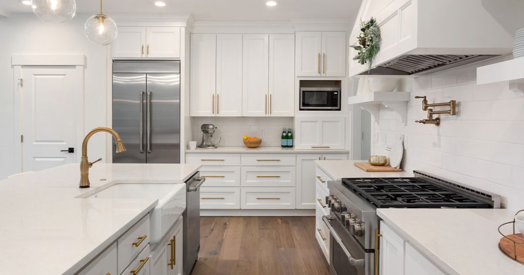 Luxury white kitchen with gold accents, quartz countertops, and stainless steel appliances