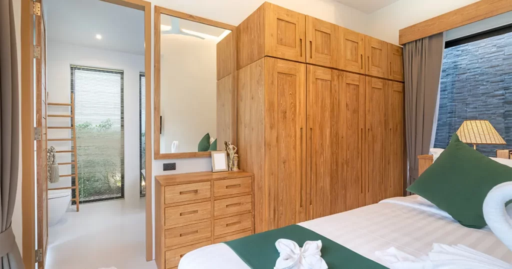 Built-in wooden closet with overhead cabinets and mirror in modern bedroom