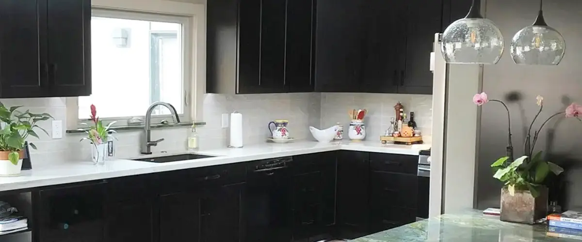 Dark custom kitchen cabinets with white countertops and pendant lights